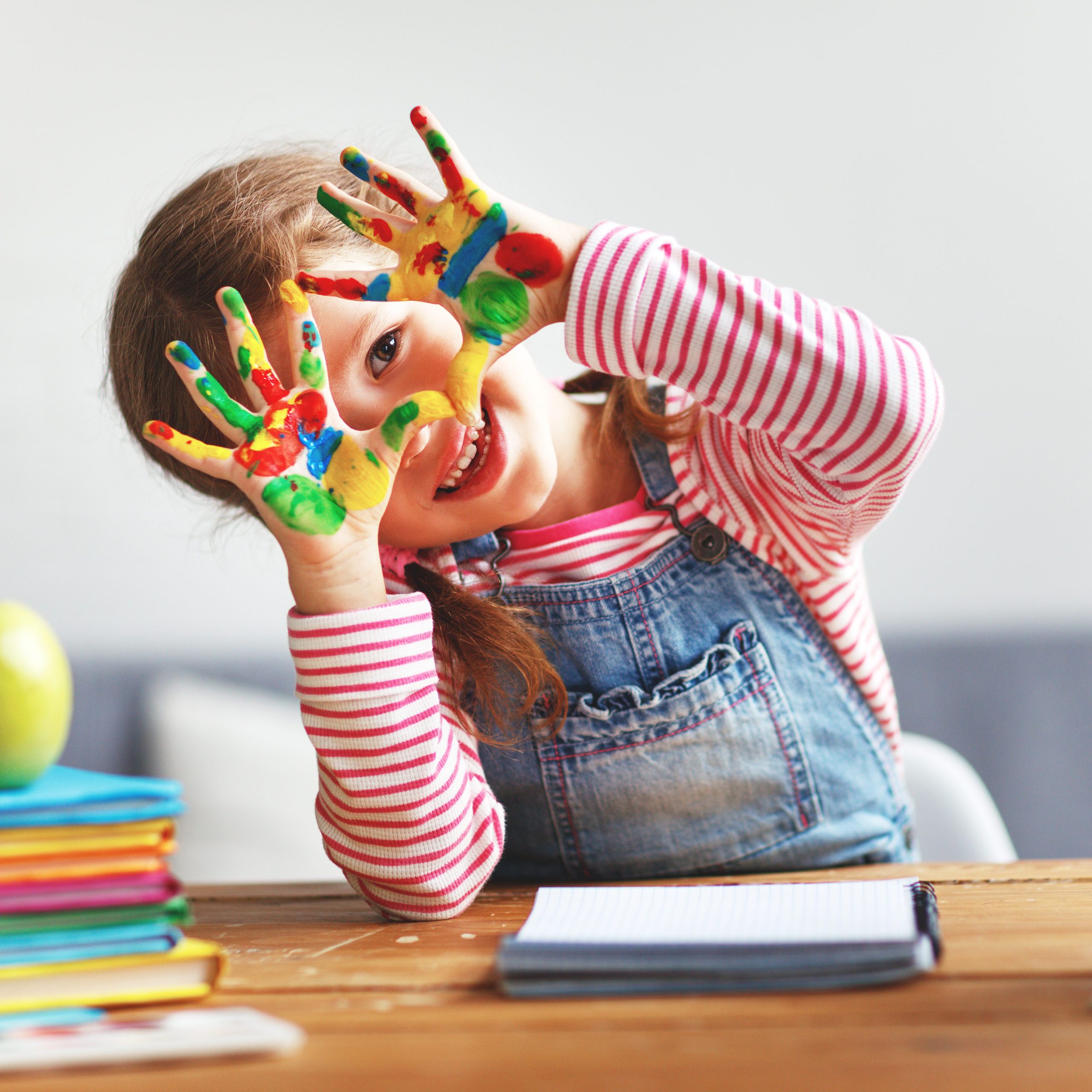 Niña de pre-escolar con las manitas pintadas de colores