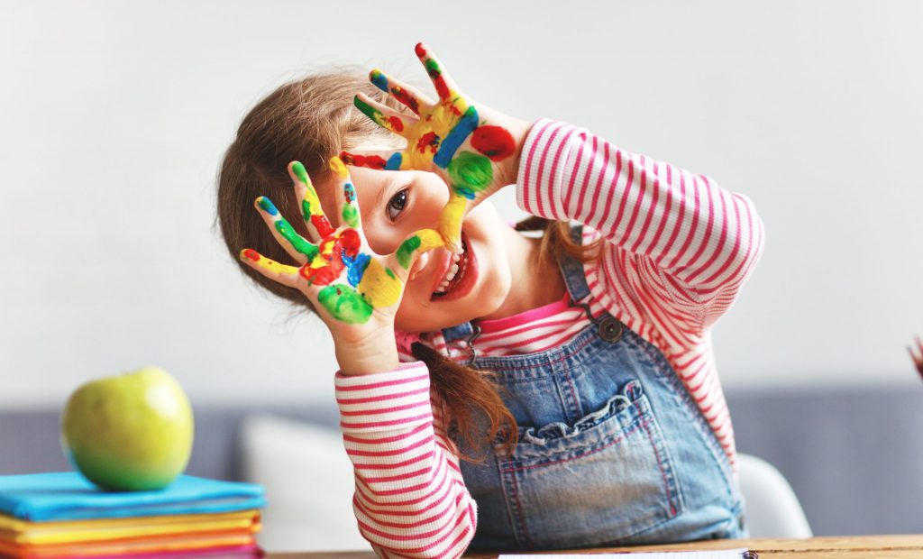 Niña de pre-escolar con las manitas pintadas de colores