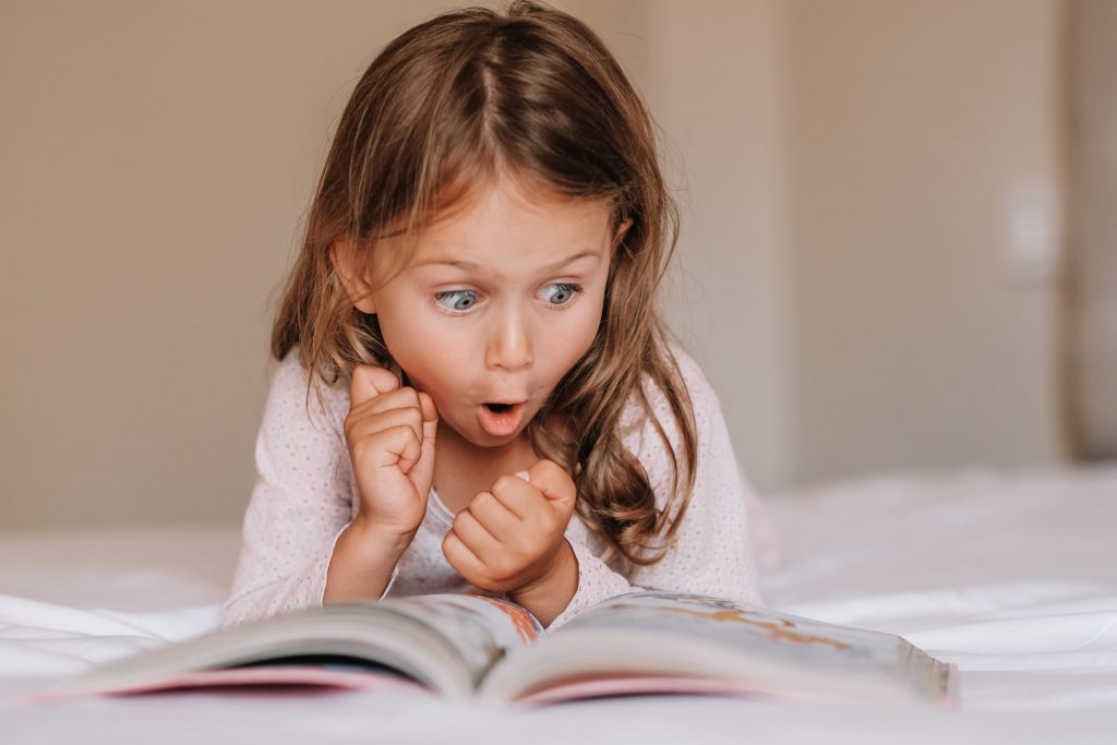 Niña leyendo con asombro