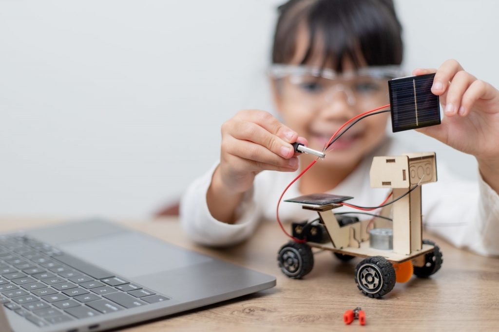Niña instalando sensor fotovoltaico en pequeño robot de cartón