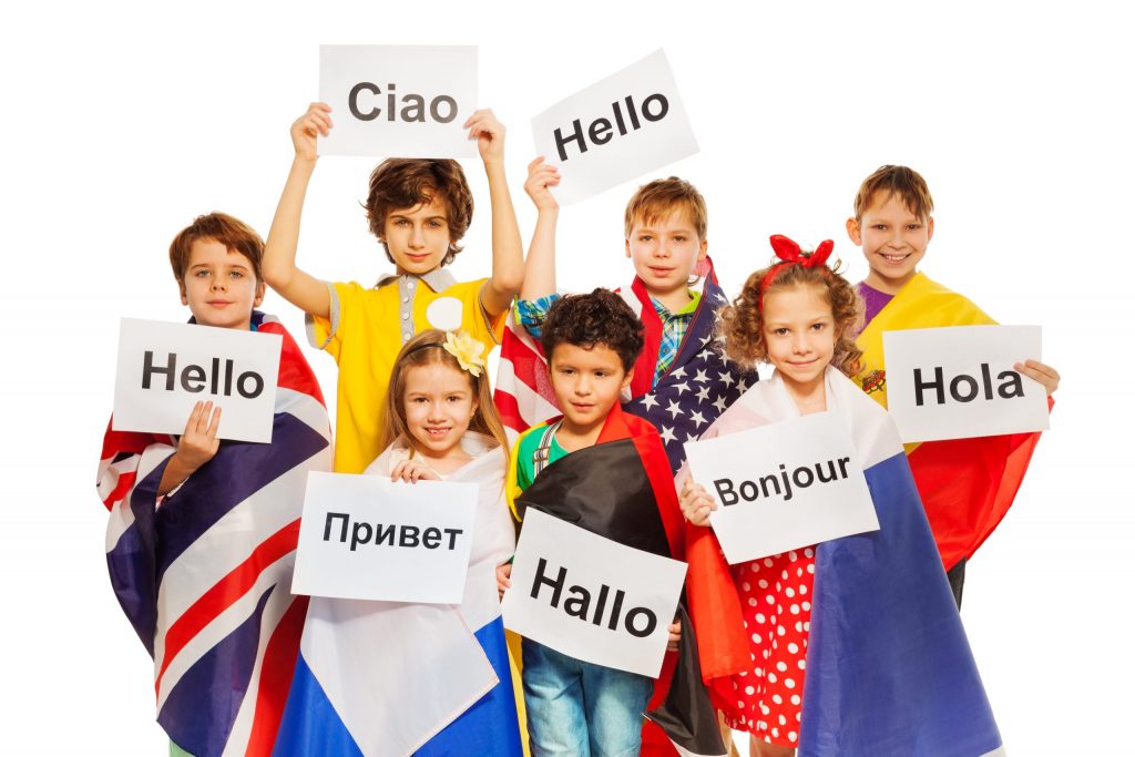 Grupo de niños con banderas y rótulos con saludos en cada idioma